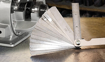 A feeler gauge measuring tool next to a rotary airlock valve.