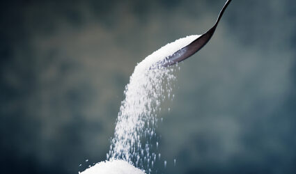 A stream of white sugar falling from a spoon