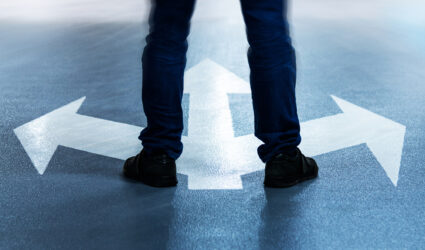 Man's legs standing on arrows pointing in three directions.