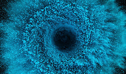Blue dust spiraling out from the center of a black background
