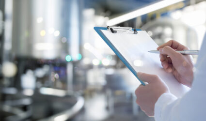 Hands holding a checklist in a manufacturing facility
