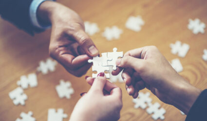 Hands putting puzzle pieces together for a custom solution
