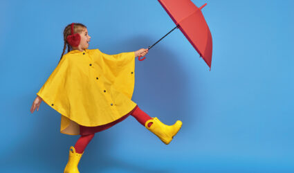 Child in Rain boots and jacket with umbrella