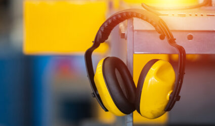 A pair of yellow construction headphones hanging on a metal shelf