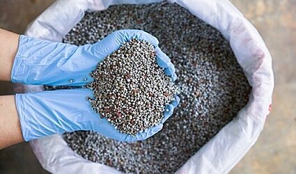 Gloved hands scooping fertilizer mix out of a bag