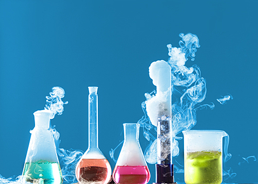 lab beakers and flasks filled with colourful liquid giving off fumes