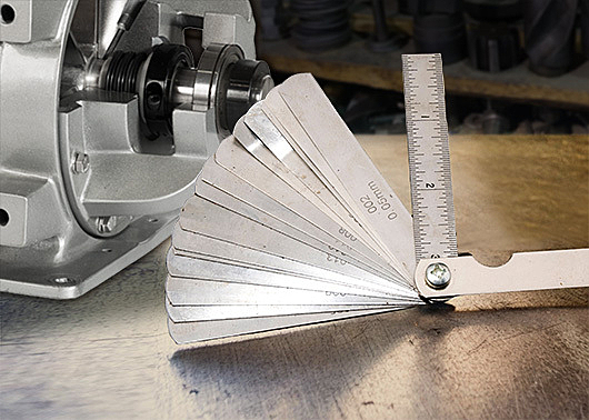 A feeler gauge measuring tool next to a rotary airlock valve.