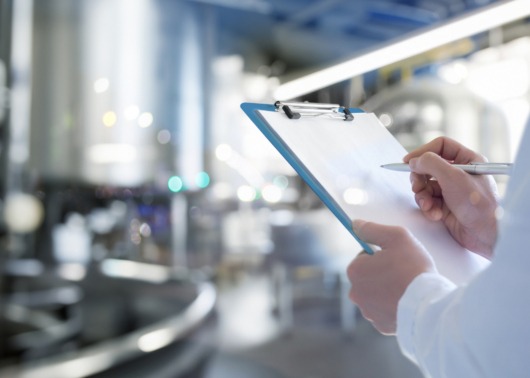 Hands holding a checklist in a manufacturing facility