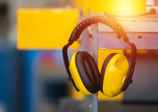 A pair of yellow construction headphones hanging on a metal shelf