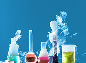 lab beakers and flasks filled with colourful liquid giving off fumes