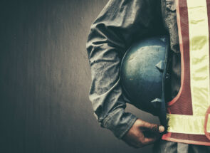 Worker in safety gear holding a construction helmet