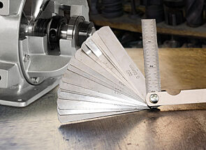 A feeler gauge measuring tool next to a rotary airlock valve.