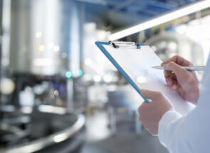 Hands holding a checklist in a manufacturing facility