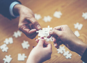 Hands putting puzzle pieces together for a custom solution