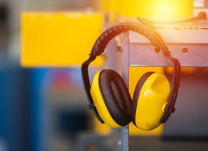 A pair of yellow construction headphones hanging on a metal shelf