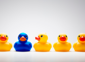 Several yellow rubber ducks in a row with one blue duck in the middle