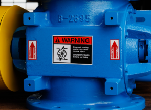 A blue ACS Valves rotary airlock valve with safety stickers