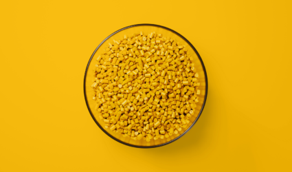 Bowl of Yellow plastic pellets with a yellow background.