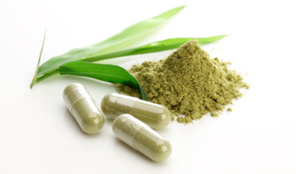Green powder with capsules with green powder in it.
