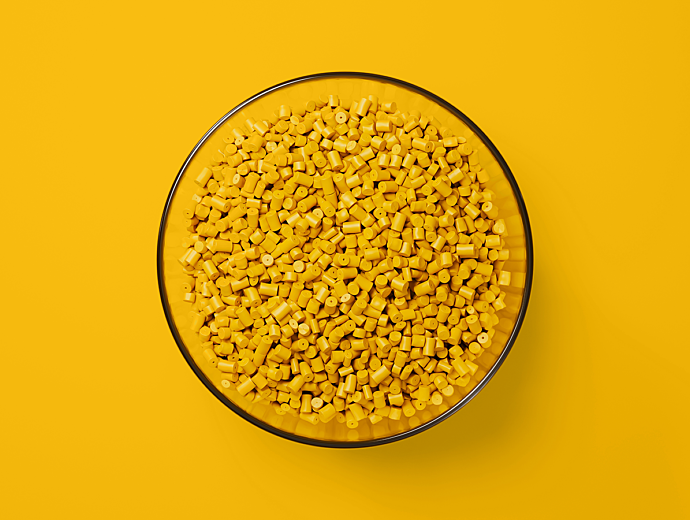 Bowl of Yellow plastic pellets with a yellow background.