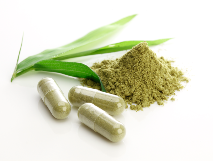 Green powder with capsules with green powder in it.